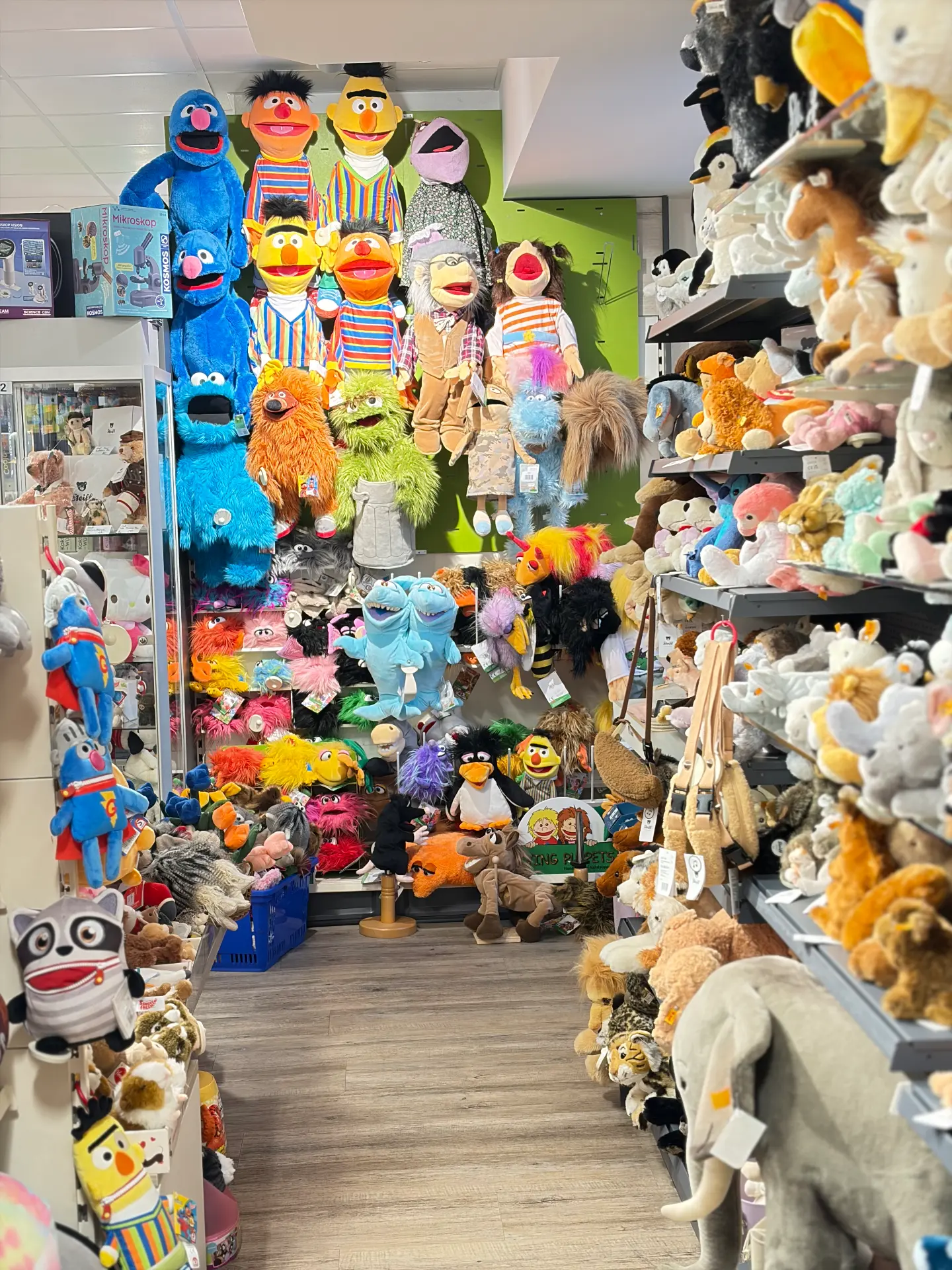 Wand voller bunter Handpuppen, daneben Regale mit Plüschtieren