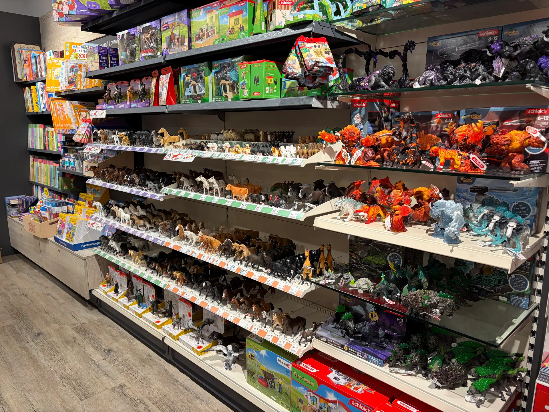 Regalmeter mit Schleich-Spielfiguren wie Pferden und Bauernhoftieren, daneben Kinderbücher