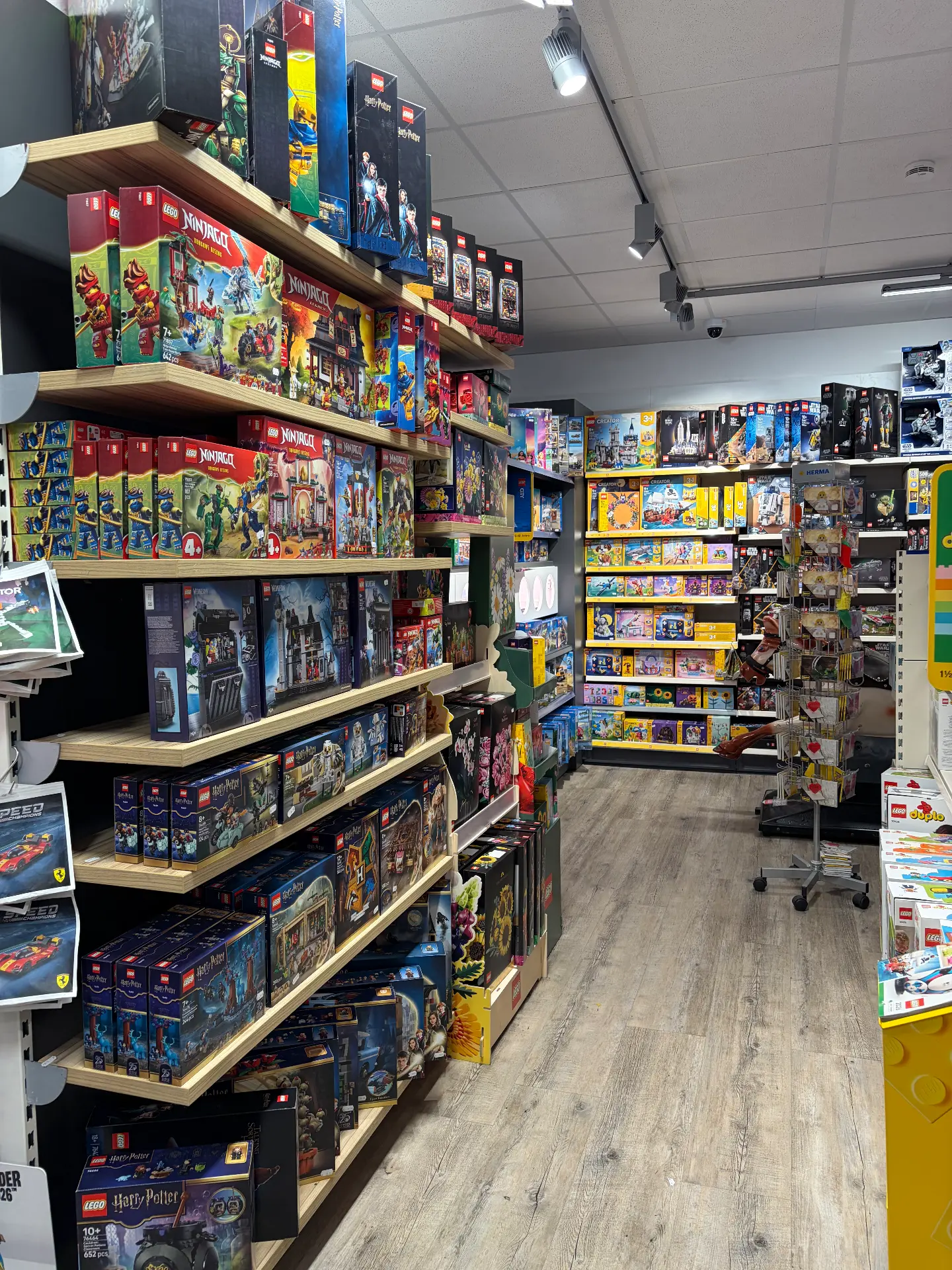 Gang mit Holzregalen voller LEGO-Sets der Reihen Ninjago, Harry Potter und City